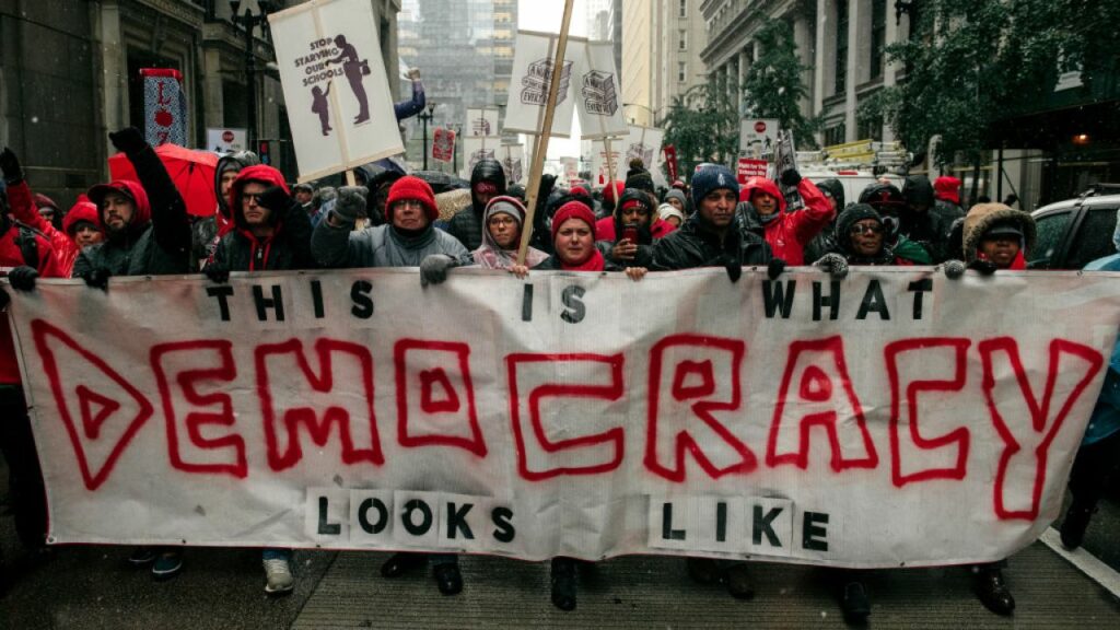 Chicago Teachers Union march in front of banner, "This is what democracy looks like"