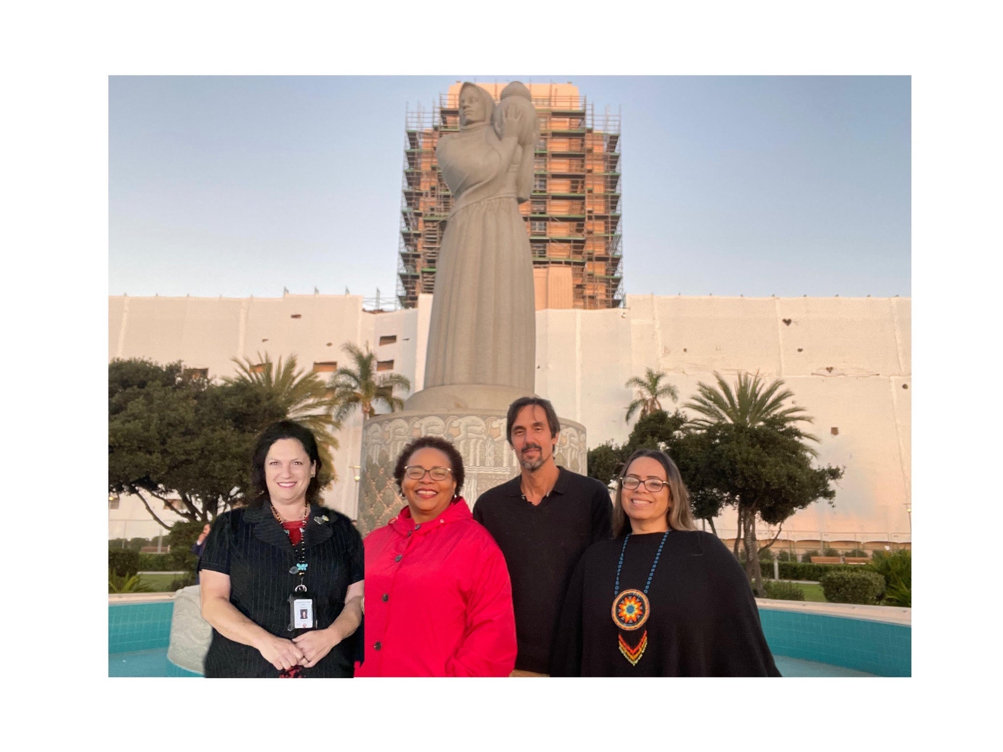 Maria Whitehorse junto a otros tres activistas frente a una estatua gigante de una mujer que sostiene una olla frente al edificio de administración del condado de San Diego. Crédito: María Whitehorse.
