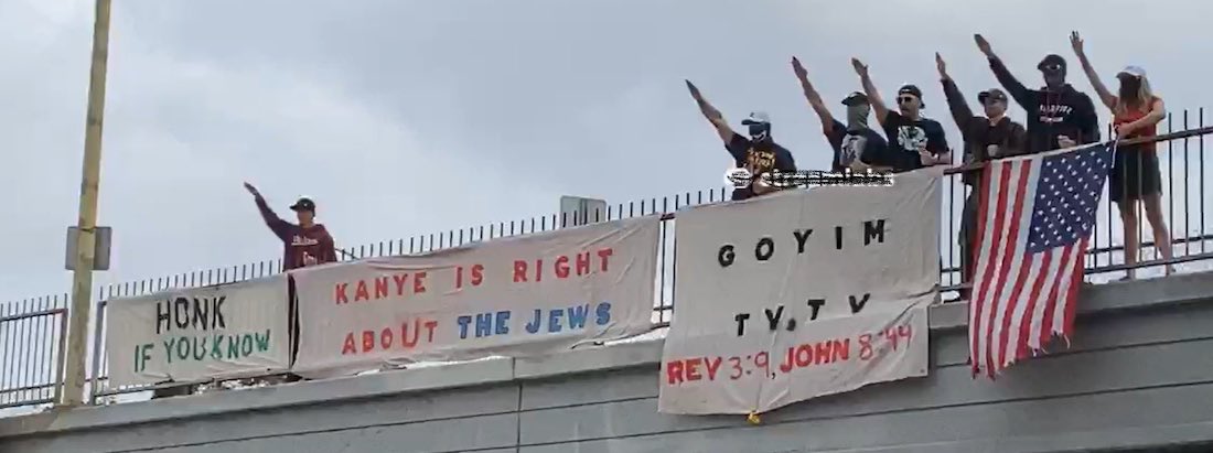 Members of the white supremacist Goyim Defense League drop banners over a highway in Los Angeles— proclaiming, among other things, “Honk if you know…Kanye is right about the Jews”—while waving a U.S. flag and making fascist one-armed salutes