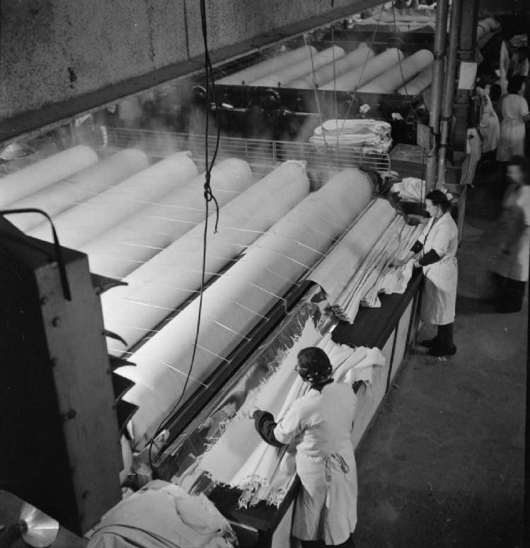 Women work at huge industrial laundry rollers in 1944 under a planned economy.