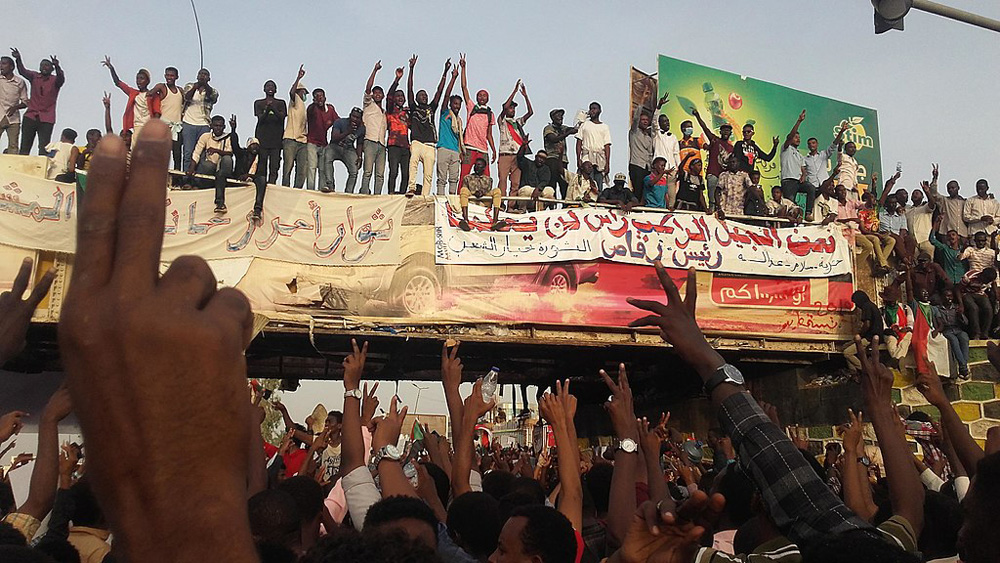 Masses of people celebrate on a bridge in Khartoum waving banners in 2019.