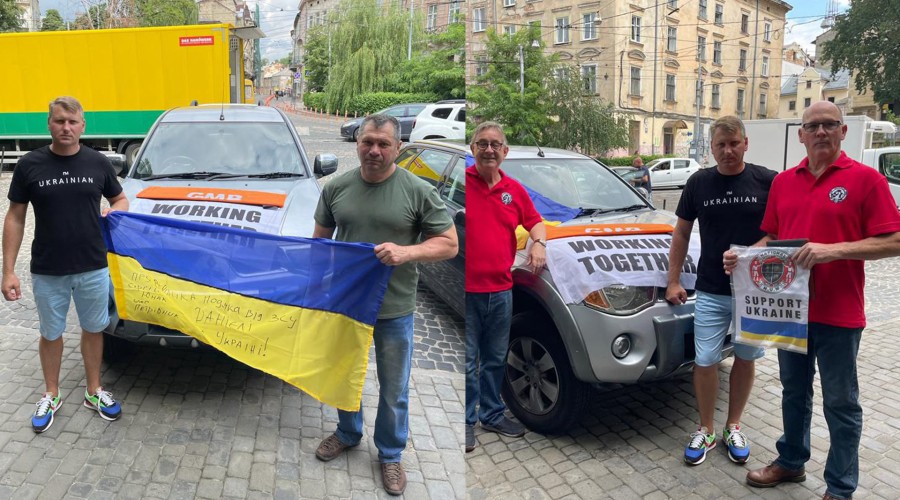 Two photos show different sets of people standing in front of the same vehicle, a silver four by four pickup vehicle. The vehicle has a flag laid on top of its front hood that says “GMB. WORKING TOGETHER.” The left image shows a person wearing a t-shirt that says ‘UKRAINIAN’ holding the left corner of a Ukrainian flag that has a handwritten message written on the flag’s yellow stripe. The message’s lettering are too faint to discern specific words. Another person holds the right corner of the flag. The right image captures the same person wearing the shirt that says ‘UKRAINIAN’ with two people wearing red shirts with the British National Union of Mineworkers logo. One of them holds up a piece of fabric with text that says ‘SUPPORT UKRAINE.’ Above the text is the NUM logo and below is the Ukrainian flag.