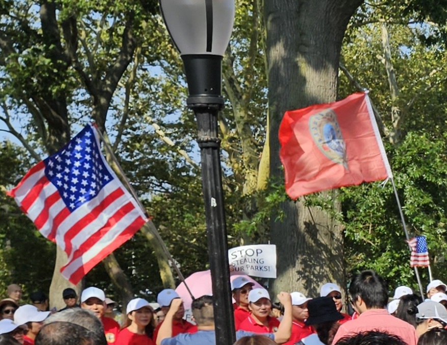 Protesters wave American flags in a crowded street protest.