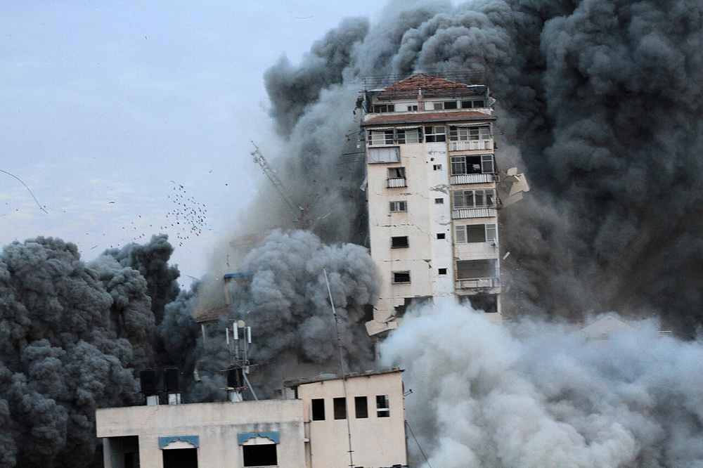 Smoke and debris from a bomb rise around a damaged tower block in Gaza.