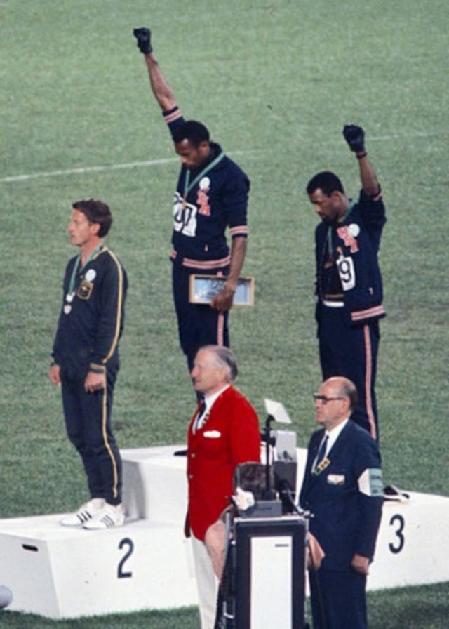 American sprinters Tommie Smith and John Carlos, along with Australian Peter Norman, during the award ceremony of the 200 m race at the Mexican Olympic games. Photo shows the awards ceremony, Smith (center) and Carlos protesting against racial discrimination: they went barefoot on the podium and listened to their anthem bowing their heads and raising a fist with a black glove. Mexico City, Mexico, 1968.