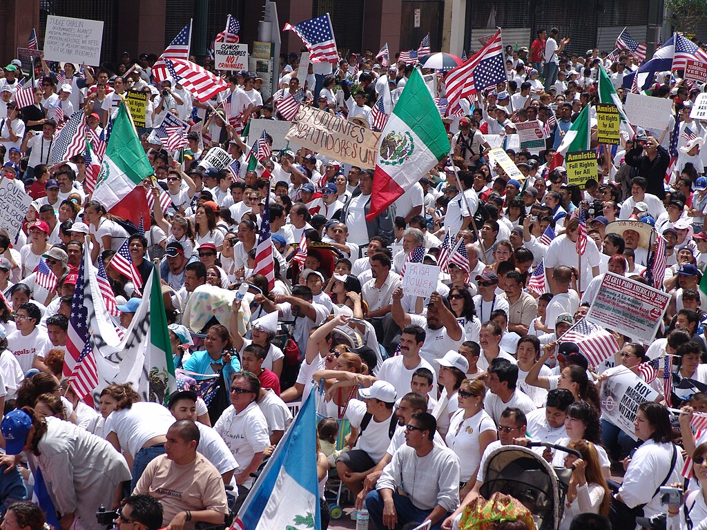 A massive crowd holding signs demanding justice for immigrants. There are American and Mexican flags.